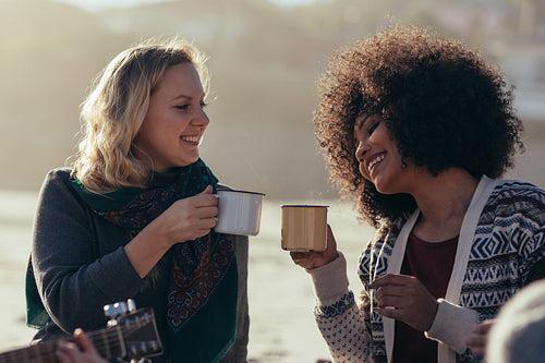 Female friends having coffee at the beach
