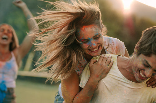 Happy couple enjoying holi with friends in a park