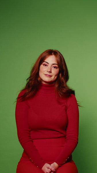 Smiling young woman in a red dress on a green screen background