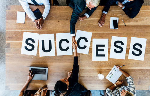 Businesspeople handshake with word success on table