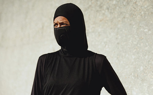 Muslim woman wearing face mask taking break from workout