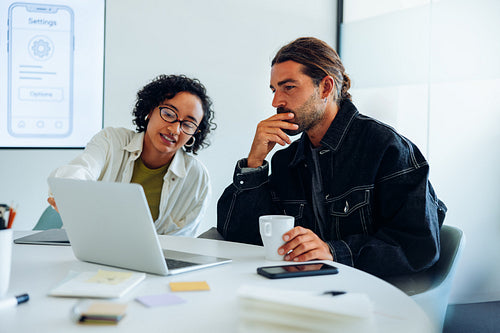 Colleagues collaborating with focus during design meeting at desk