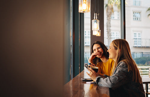 Two women sitting at a cafe and smiling