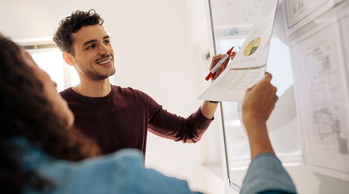 Business colleagues discussing work on a whiteboard in office
