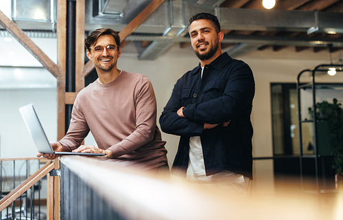 Male business professionals standing together on an interior balcony