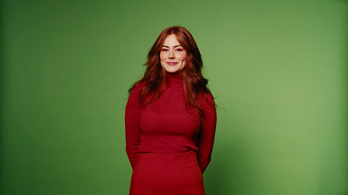 Happy redhead woman in red outfit laughs and smiles on green screen