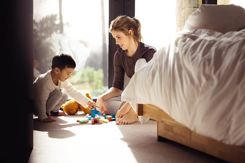 Woman looking at her son playing blocks indoors