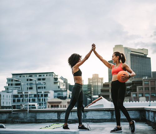 Fitness women giving high five during workout on rooftop