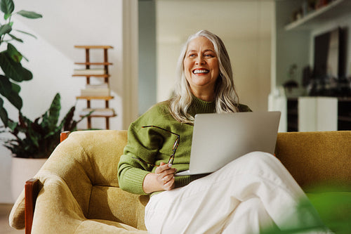 Senior woman uses laptop on sofa at home