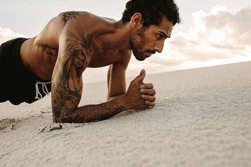 Athlete doing core workout on sand dun
