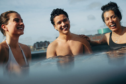 A city skyline surrounds the spa as friends relax in warm water.