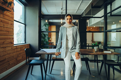 Muslim entrepreneur standing in a modern boardroom