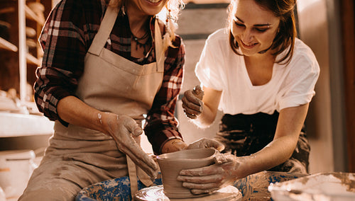 Two women at a pottery workshop making clay pots