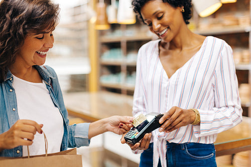Happy female customer paying her bill with a credit card in a ceramic store