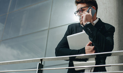 Businessman talking on mobile phone holding a laptop