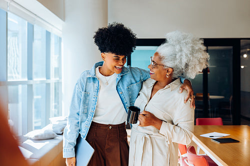 Two women share a warm moment in an office space