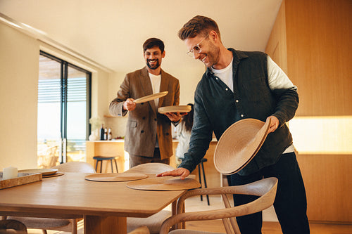 Friends preparing the dinner table in modern sunlit home