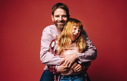 The warm family portrait shows a father and daughter laughing together with a hug