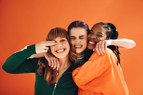 Multicultural female friends smiling and embracing each other in a studio