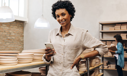 Female ceramist smiling at the camera in her shop