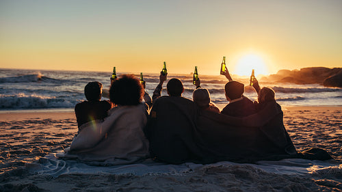 Group of friends enjoying beach sunset with beers