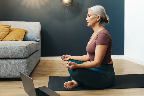 Woman meditating in lotus pose, achieving balance and harmony through yoga