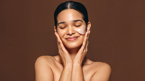 Woman with smooth skin enjoys using a hydrogel patch on her skin, an undereye mask used for anti-aging