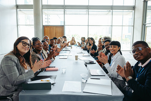 First-person view of people clapping at a business meeting around a long table