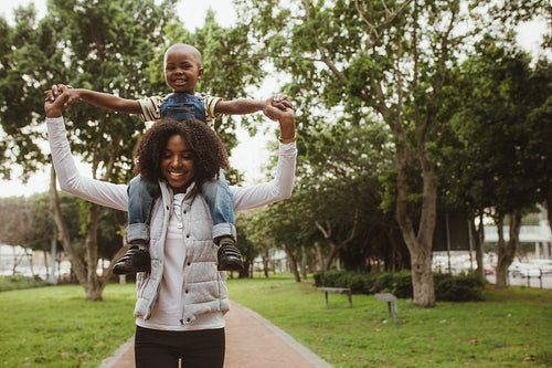 Mother carrying boy on shoulders at park
