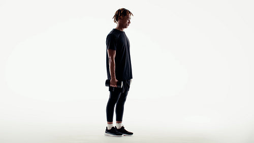 A man performing lunges with a dumbbell in a clean studio for fitness