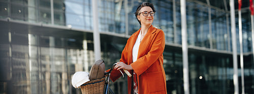 Thoughtful businesswoman pushing her bike during her morning commute in the city