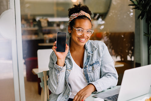 Young woman smiling and recommending a mobile app on her phone