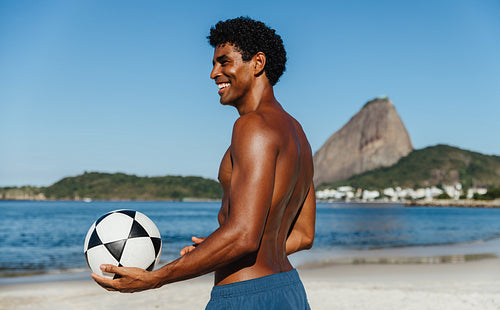 Man enjoying football on a sunny Brazilian beach with iconic landscapes