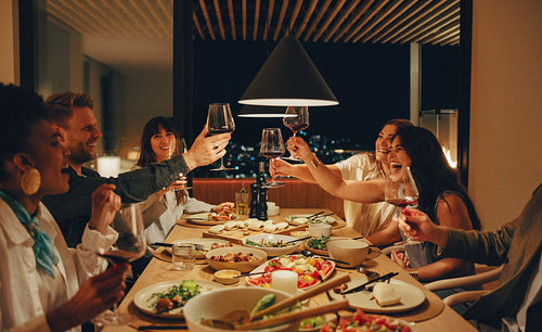 A group of friends enjoying food and drinks together at night
