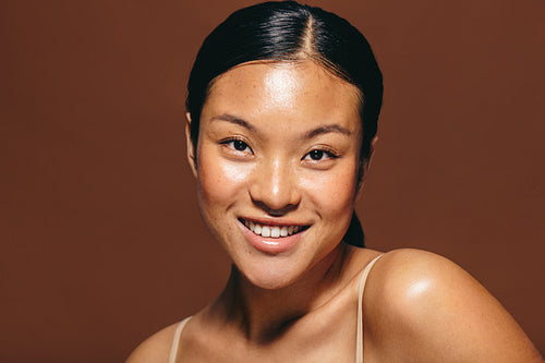 Portrait of a young woman with glowing skin smiling with confidence and radiance