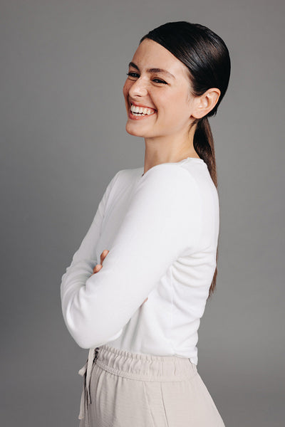 Happy young woman laughing while standing against a grey background