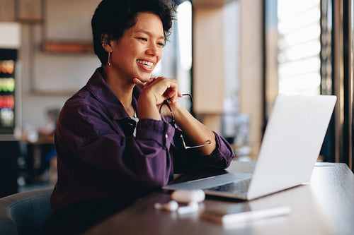Smiling businesswoman working on laptop at cafe