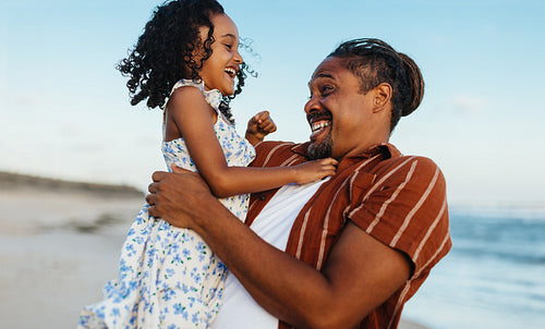 Happy father and daughter playing at the beach on a sunny day