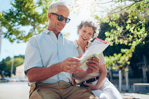 Mature couple sitting outdoors with a city map