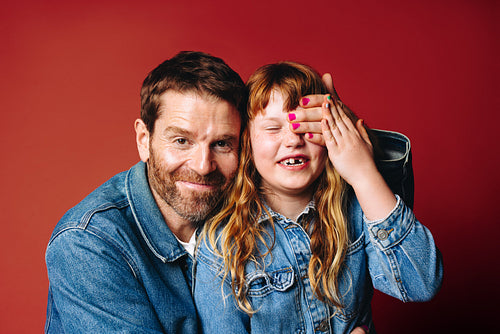 Father and daughter share a playful smiling family portrait together