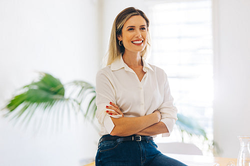 Smiling businesswoman sitting with her arms crossed