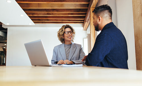 Two business people having a meeting. Man and woman talking to each other in an office
