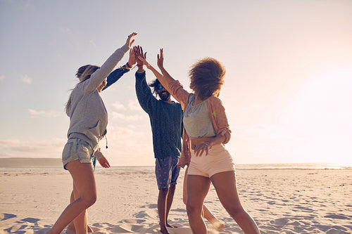 Group of happy friends high fiving on the beach