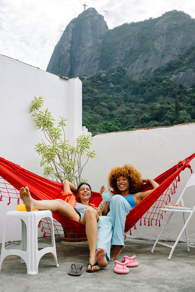 Two women relaxing on a hammock with Cristo Redentor in the background