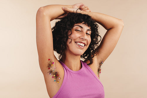 Confident young woman flaunting her confetti-decorated arm pits