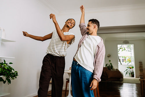 Smiling gay couple dancing together in their cozy home living room