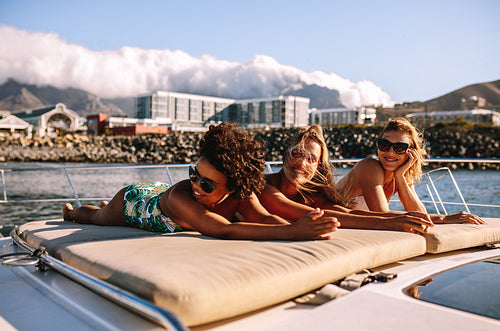 Female friends sunbathing on the bow of a luxury yacht