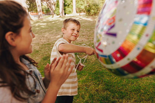 Children enjoying a colorful outdoor birthday party with balloons and games