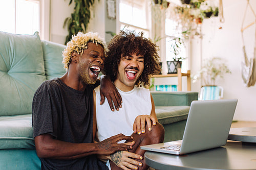 Lovely gay couple laughing together at home