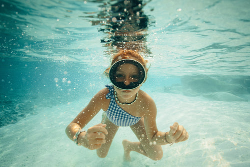 Young girl swimming underwater on a tropical island trip in clear blue water